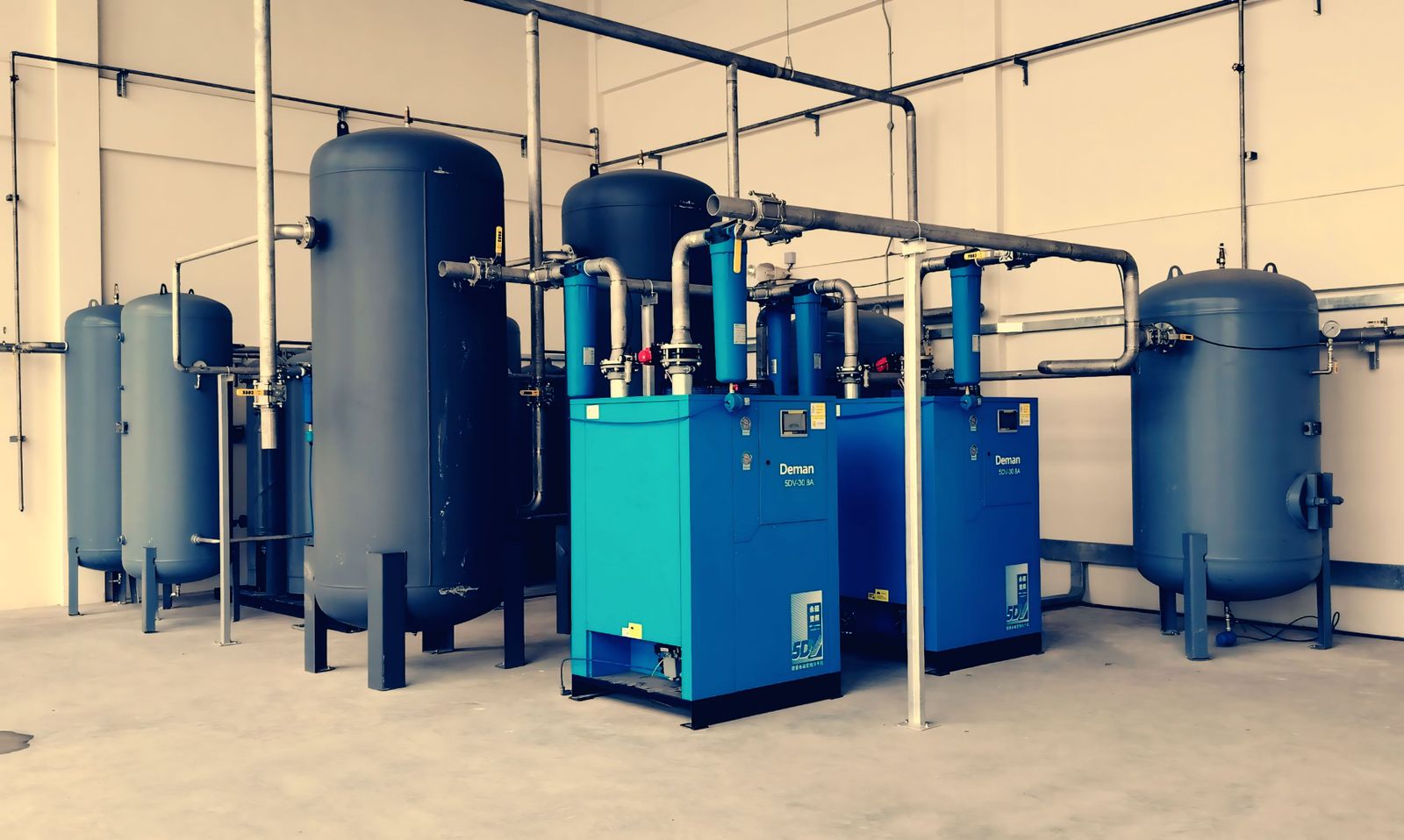 Sistema de compresores de aire con depósitos azules y tuberías en una planta