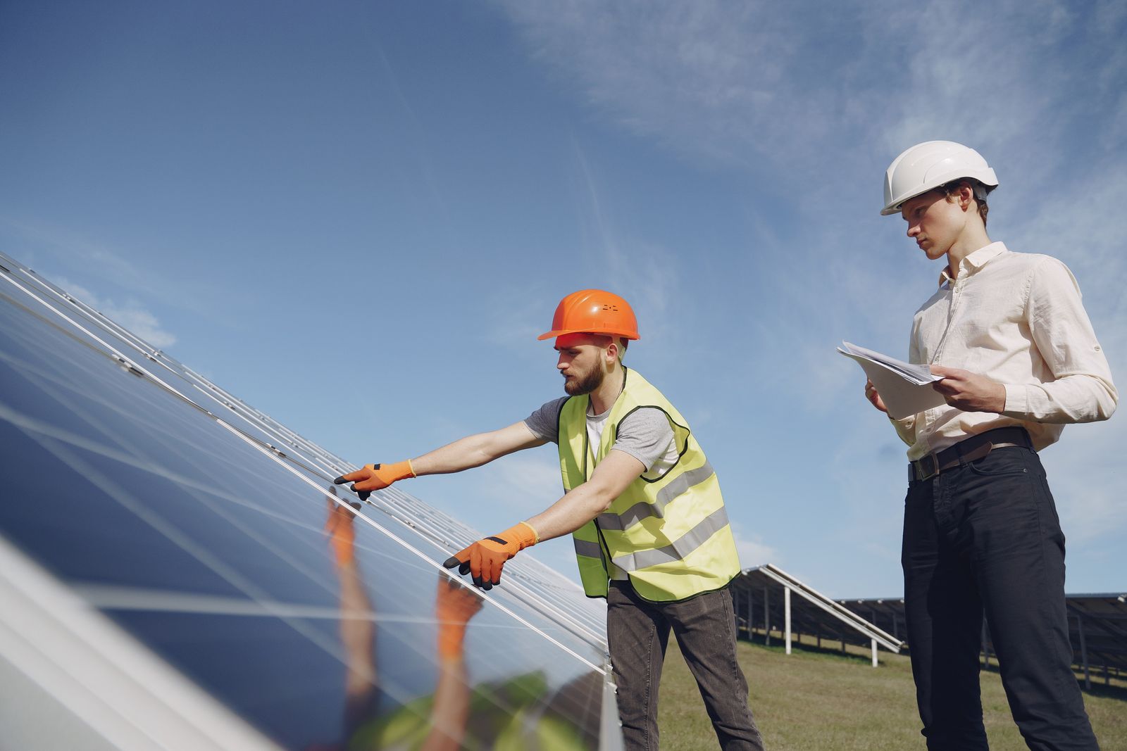 Dos especialistas con casco inspeccionando una instalación de paneles solares
