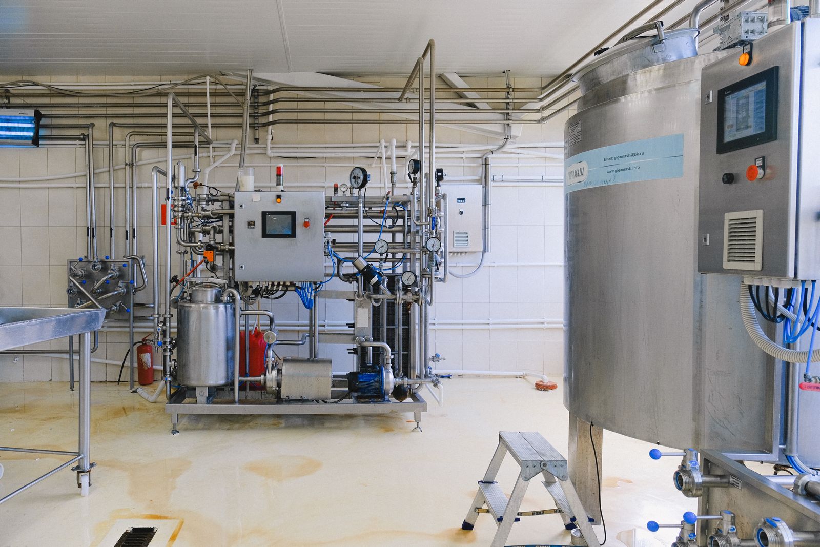 Equipos de proceso con depósitos de acero inoxidable y tuberías en una sala industrial